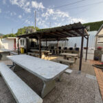 Zona exterior con mesas de piedra y barbacoa